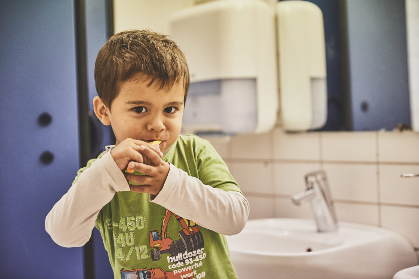 Ein kleiner Junge steht im Bad der Kita und putzt sich die Zähne.