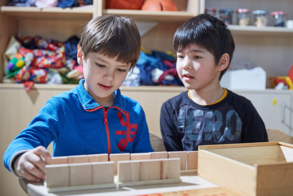 Zwei Jungs beschäftigen sich im Spielzimmer gemeinsam mit einer Kiste.