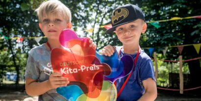 Zwei Kinder halten die Trophäe des Kita-Preises