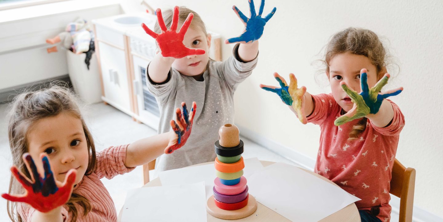 Kinder haben ihre Hände farbig angemalt
