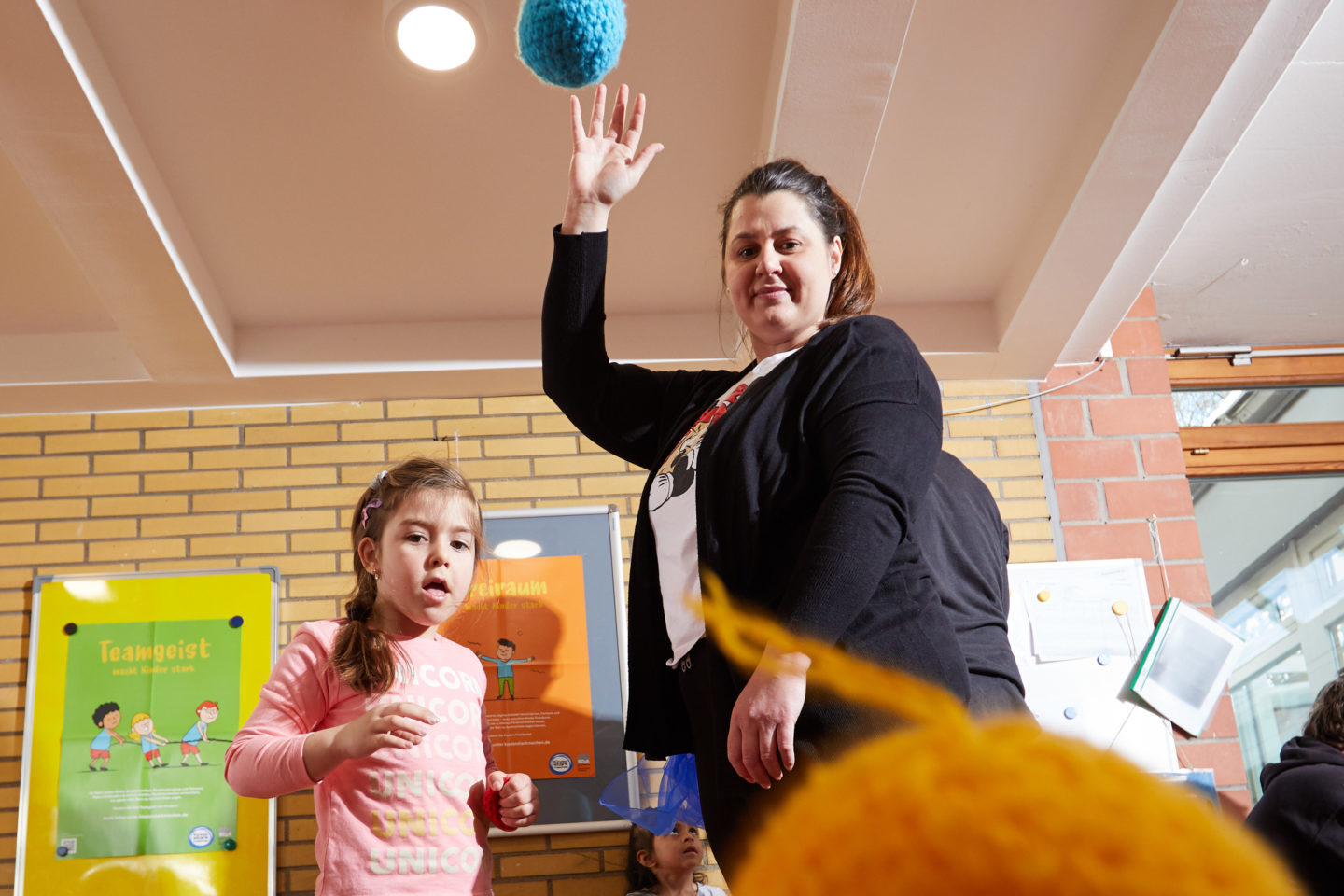 Mutter und Kind spielen mit einem Ball.