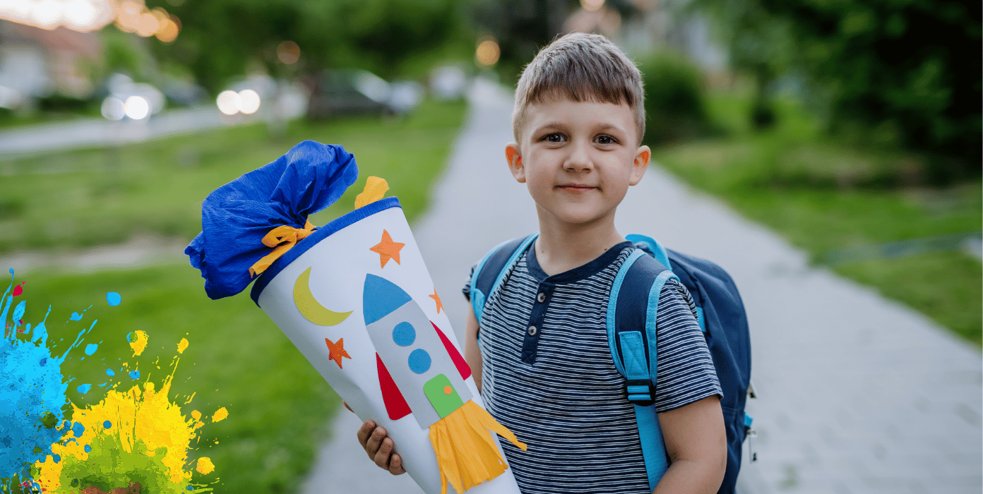 Kleiner Junge mit einer hellblauen Schultüte, die mit einer Rakete verziert ist.