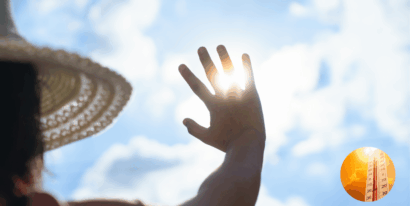 Eine Hand blockiert die Sonne am Himmel, während ein Thermometer die Temperatur anzeigt.