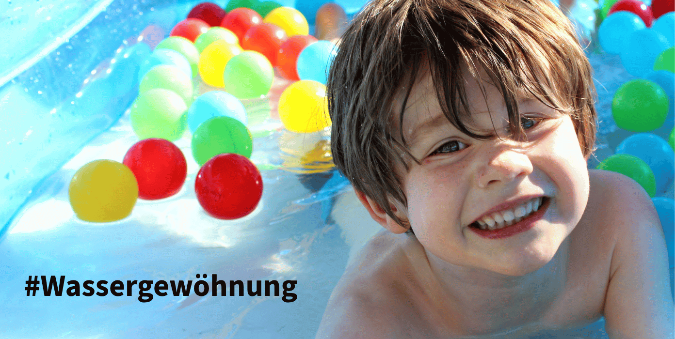 Ein fröhlicher Junge im Wasser mit bunten Bällen, ideal für Wassergewöhnung und Spielspaß.