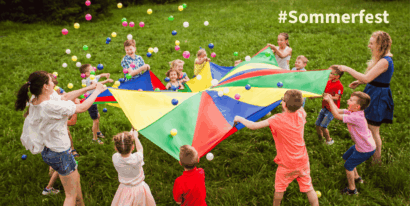 Kinder und Erwachsene spielen mit einem bunten Fallschirm im Freien beim Sommerfest.