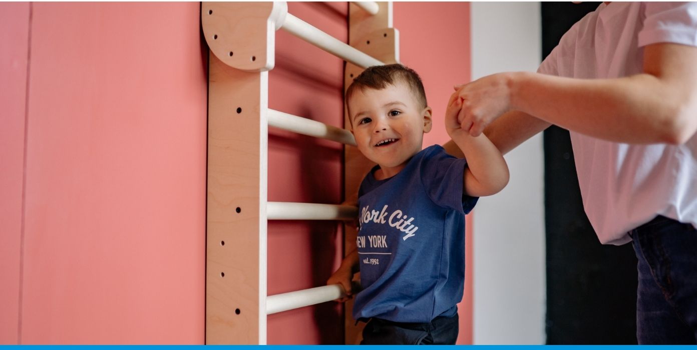 Ein Kind spielt an einer Kletterwand in der Kita, was die Aufsichtspflicht fördert und Sicherheit gewährleistet.