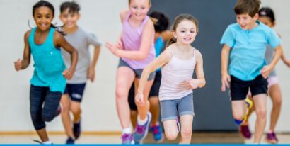 Kinder laufen fröhlich in einer Sporthalle, fördern Bewegung und Teamgeist.