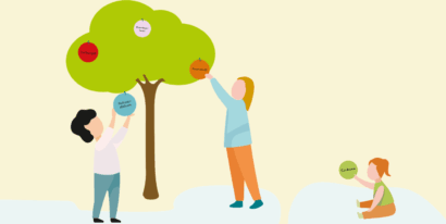 Drei Kinder spielen mit bunten Kugeln, die mit Begriffen wie Krankenhaus oder Einhorn beschriftet sind, die an einem Baum aufgehängt werden.