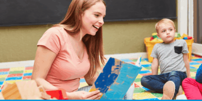 Eine junge Frau liest Kindern aus einem Bilderbuch vor.