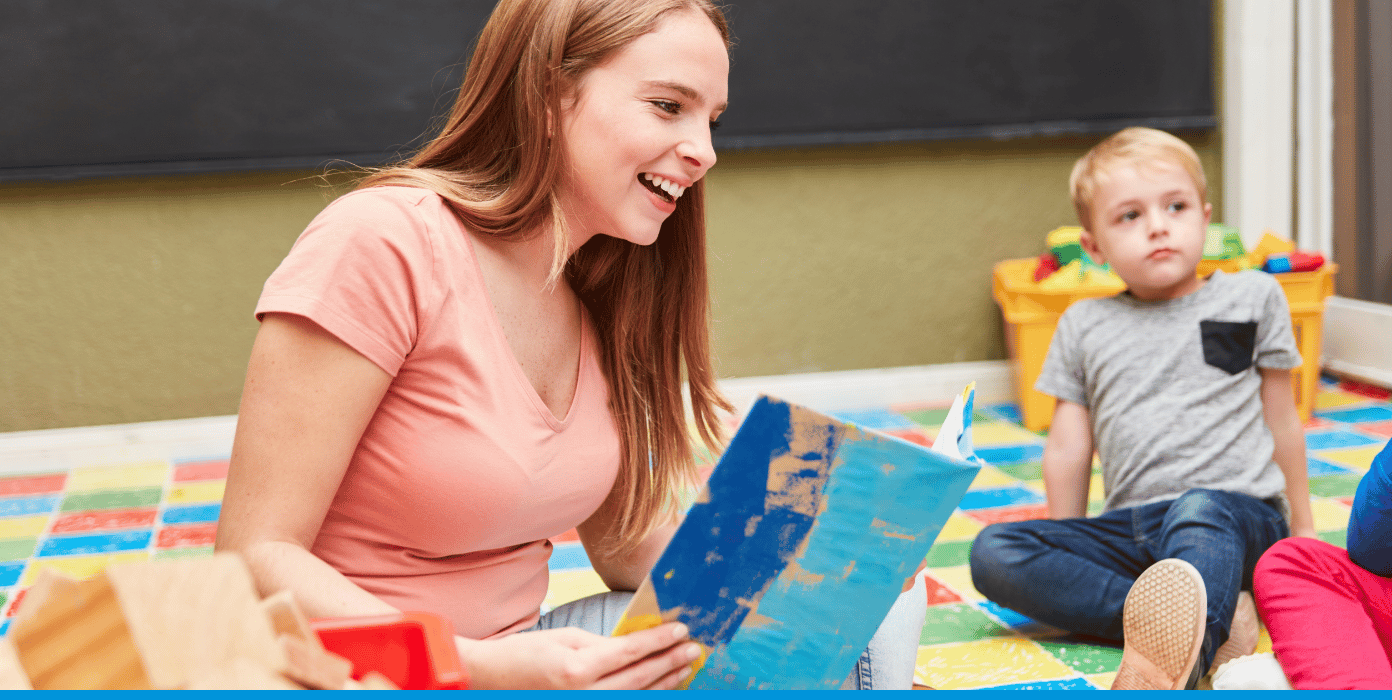 Eine junge Frau liest Kindern aus einem Bilderbuch vor.